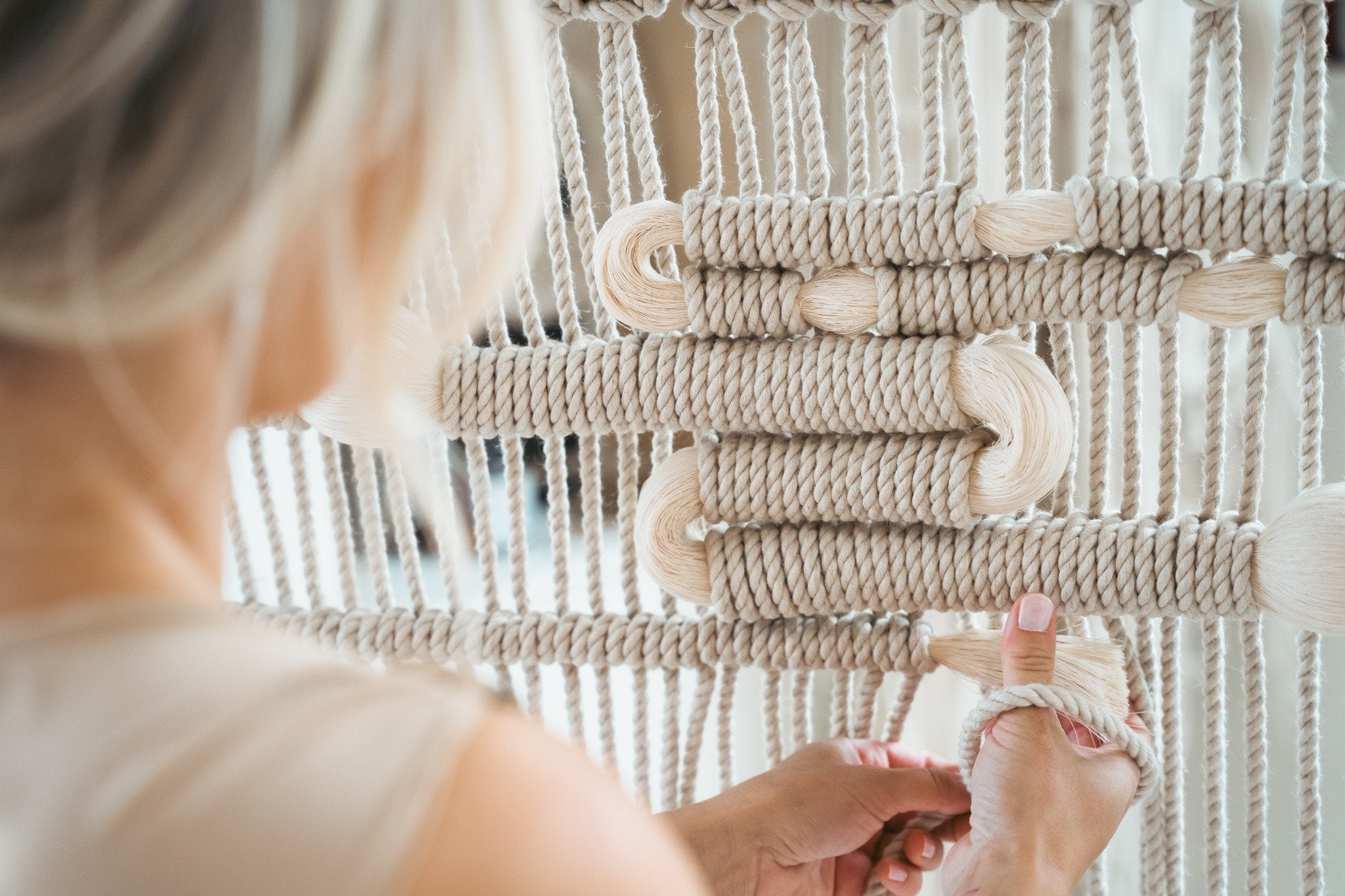 Hand-knotting a cream textile wall hanging