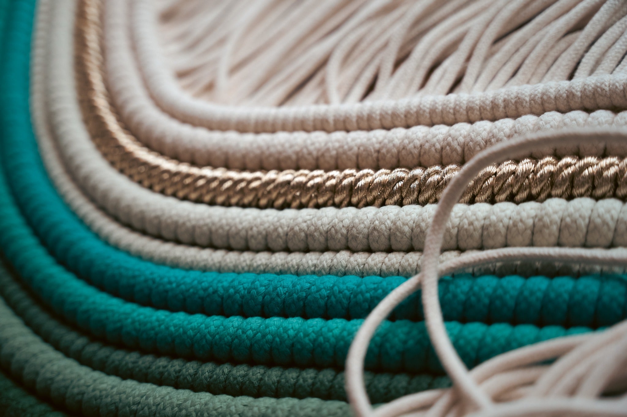Layered teal and cream cords forming a fiber artwork