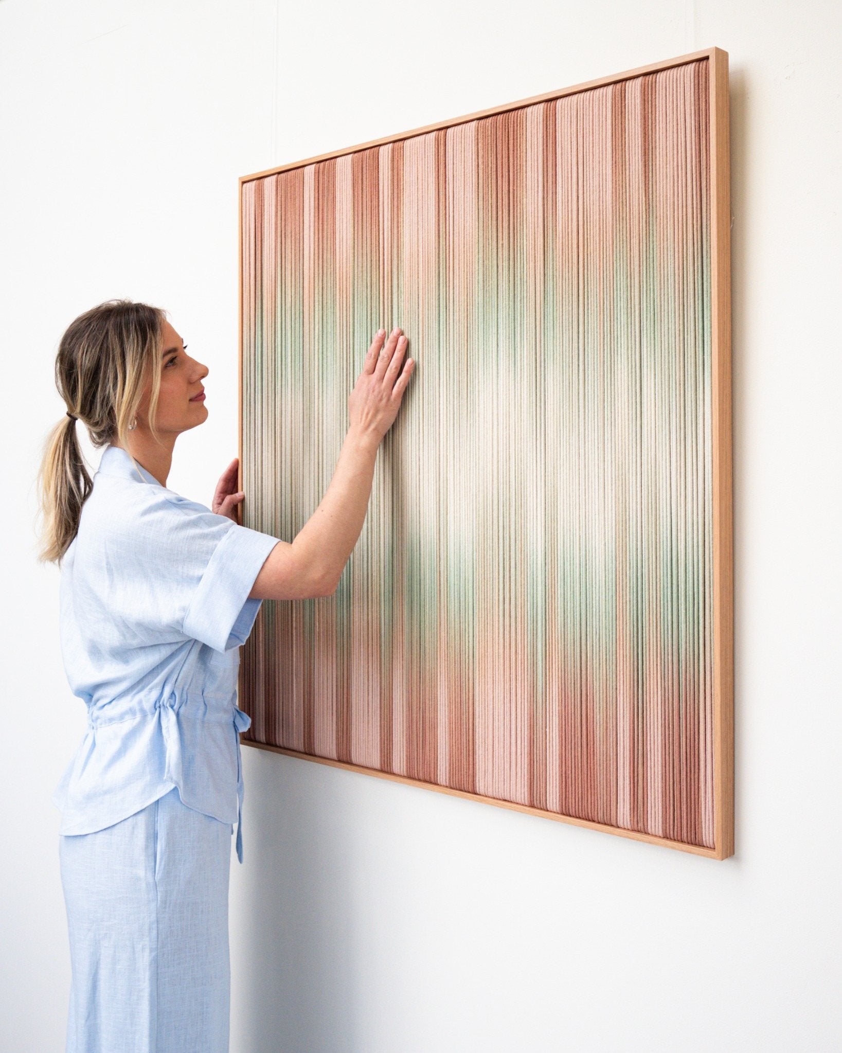 Rianne Aarts with a bespoke framed textile artwork in soft rose and sage tones