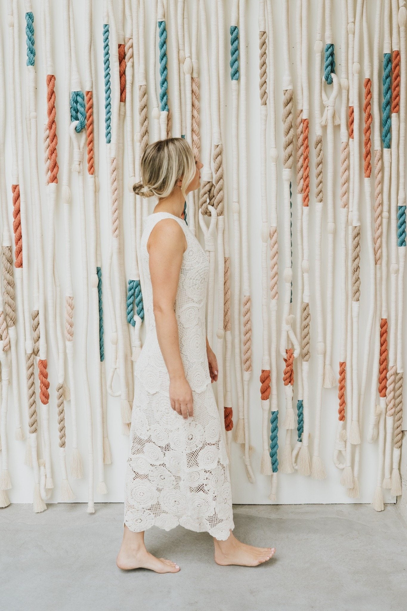 Rianne Aarts surrounded by colorful cords in her textile art studio